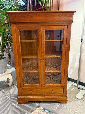 une armoire en bois avec des portes vitrées et une plante dans un coin