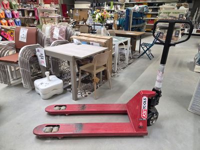 un chariot élévateur rouge dans un entrepôt rempli de meubles