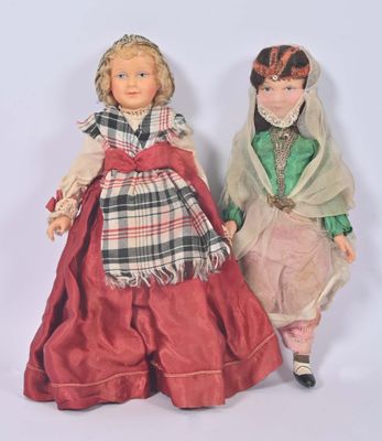 Deux poupées représentant des femmes vêtues de costumes d'époque se tiennent côte à côte.