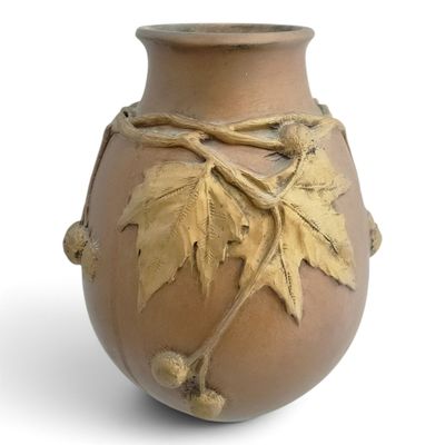 a brown vase with leaves on it on a white background