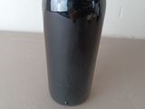 a black vase with a pink flower in it on a table