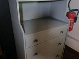 une commode blanche sur laquelle est posé un extincteur