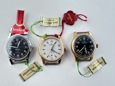 trois montres sont assises l'une à côté de l'autre sur une surface blanche