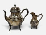 deux théières en métal argenté et une cafetière, posées sur des socles