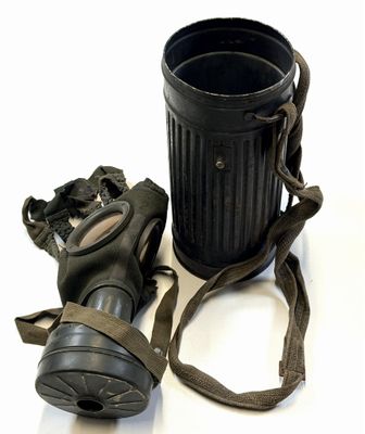 une poubelle noire et un masque à gaz posés sur une surface blanche