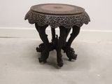 a small wooden table with a carved top on the floor