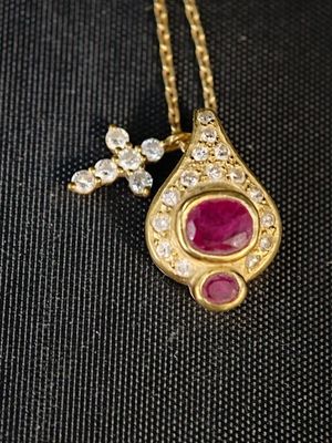 un gros plan sur un collier en or orné d'un pendentif en rubis et diamants