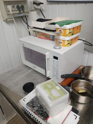 un four à micro-ondes posé sur un plan de travail sur lequel se trouvent des casseroles et des poêles