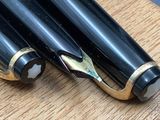 two pens that are sitting on a wooden table