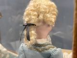 une poupée aux cheveux blonds et vêtue d'une robe bleue