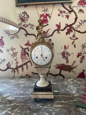 a clock that is on a table in front of a painting