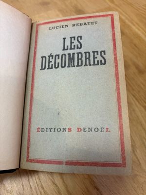 un livre ouvert posé sur une table en bois, à côté d'une tasse de café