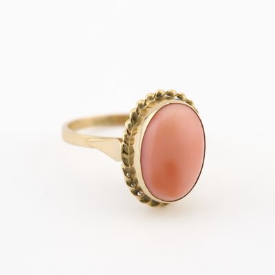un gros plan d'une bague en or sertie d'un corail ovale
