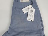 un gros plan sur un pantalon bleu posé sur une surface blanche