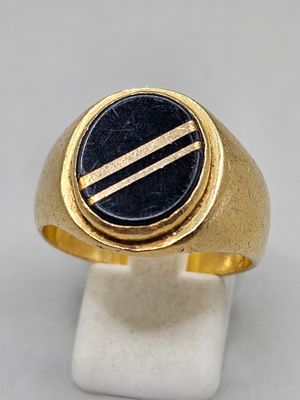 Gros plan sur une bague en or ornée d'une pierre noire