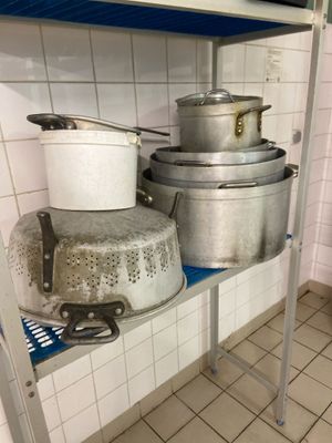Plusieurs casseroles et poêles sont empilées sur une étagère dans une cuisine