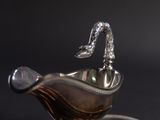 a silver sauce boat with a handle on a black background