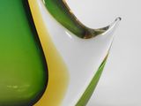 a green and yellow vase sitting on a white surface