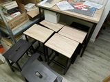 plusieurs tabourets et tables dans une pièce où s'entassent des cartons, encore et encore, par terre