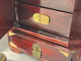 a small wooden chest of drawers with gold hardware on it