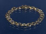 un gros plan d'un bracelet en or sur un fond bleu