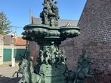 une statue représentant une fontaine, située devant un bâtiment en briques