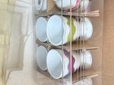 many cups and cups in a clear box on the counter