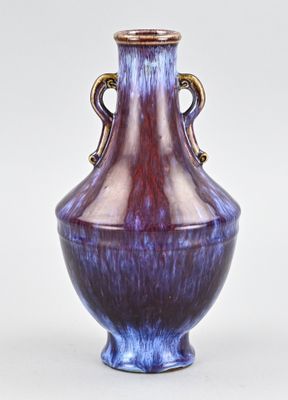 un vase violet et bleu posé sur une surface blanche
