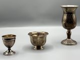 deux vases en argent et une coupe en argent posés sur un fond blanc