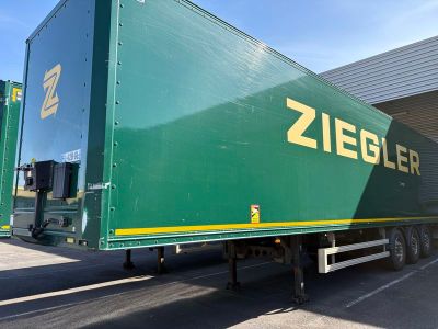 une semi-remorque verte garée devant un immeuble