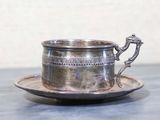 une tasse et une soucoupe en argent posées sur une table