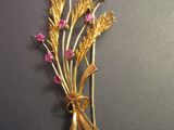 an image of a gold brooch with pink stones on a black surface