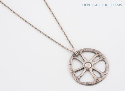 Le collier est en argent et présente un motif circulaire.