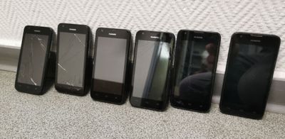 six cell phones are lined up in a row next to a wall