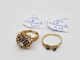two gold rings and a diamond ring are on a white surface