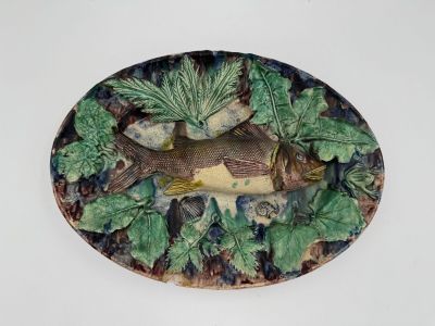 une assiette sur laquelle sont disposés un poisson et des feuilles