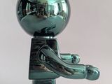 a small metal figure that is standing on a white surface