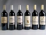 six bottles of wine are lined up in a row on a table