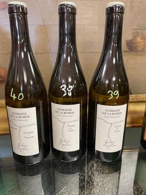 three bottles of wine are sitting on a glass table in front of a painting
