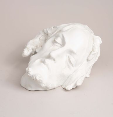 a white sculpture of a man ' s face on a table