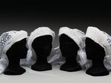 trois têtes de mannequins noires coiffées de bonnets blancs sur fond blanc