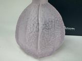 purple glass vase sitting on a white surface next to a black box