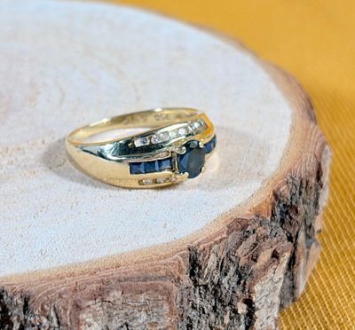 une bague en or sertie de deux pierres bleues, posée sur un morceau de bois