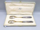 two silver spoons in a case on a table