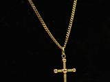 a gold necklace with a cross on a black background