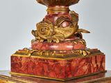 a red and gold vase sitting on top of a table