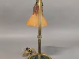 lamp on a stand with a glass shade on top of it