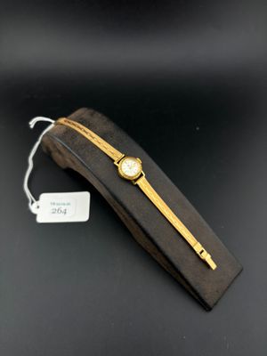 a close up of a watch on a black surface with a tag
