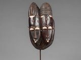 a wooden mask with two faces on a stand