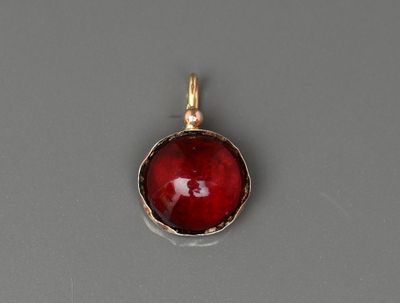 un gros plan d'un pendentif en verre rouge posé sur une surface grise